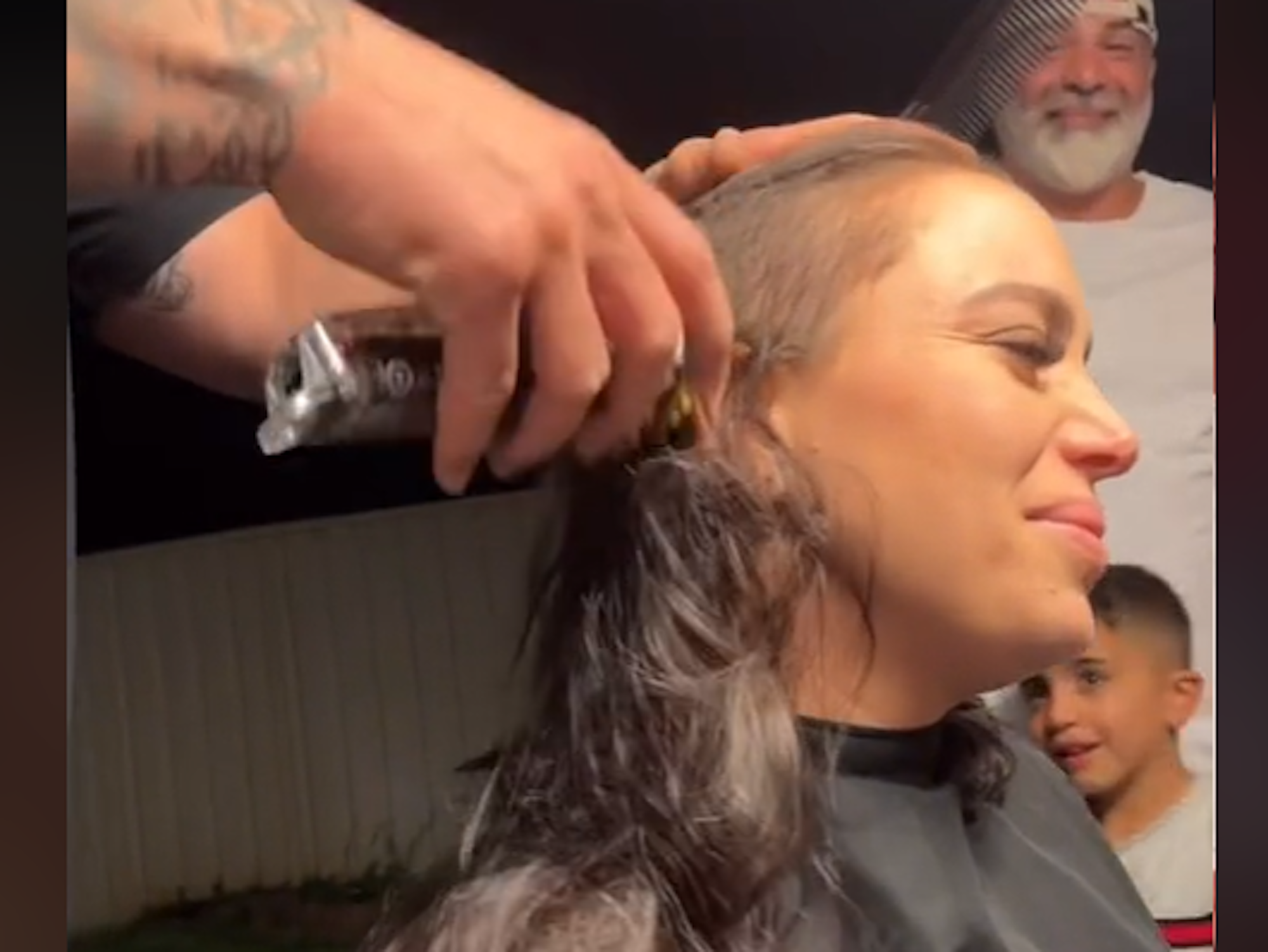 Mann rasiert den Kopf einer Frau, die das Gesicht verzehrt.