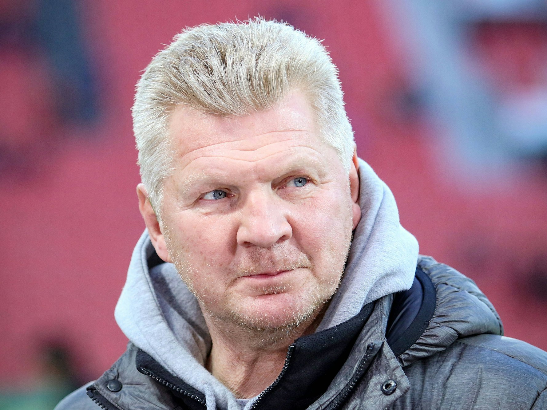 Stefan Effenberg, in Hoodie und Jacke, guckt zur Seite.