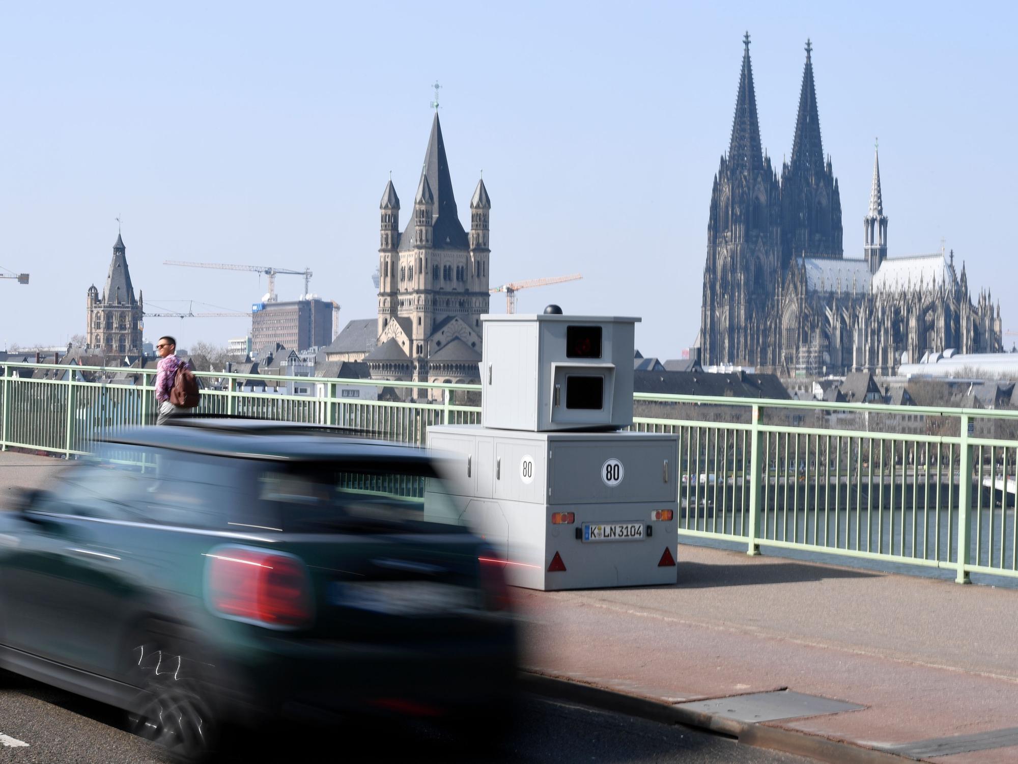 Ein Auto fährt an einem mobilen Blitzer vorbei, der mitten auf der Deutzer Brücke steht.
