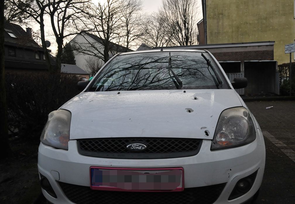 Auf der Motorhaube eines Ford Fiestas sieht man mehrere Einschusslöcher.