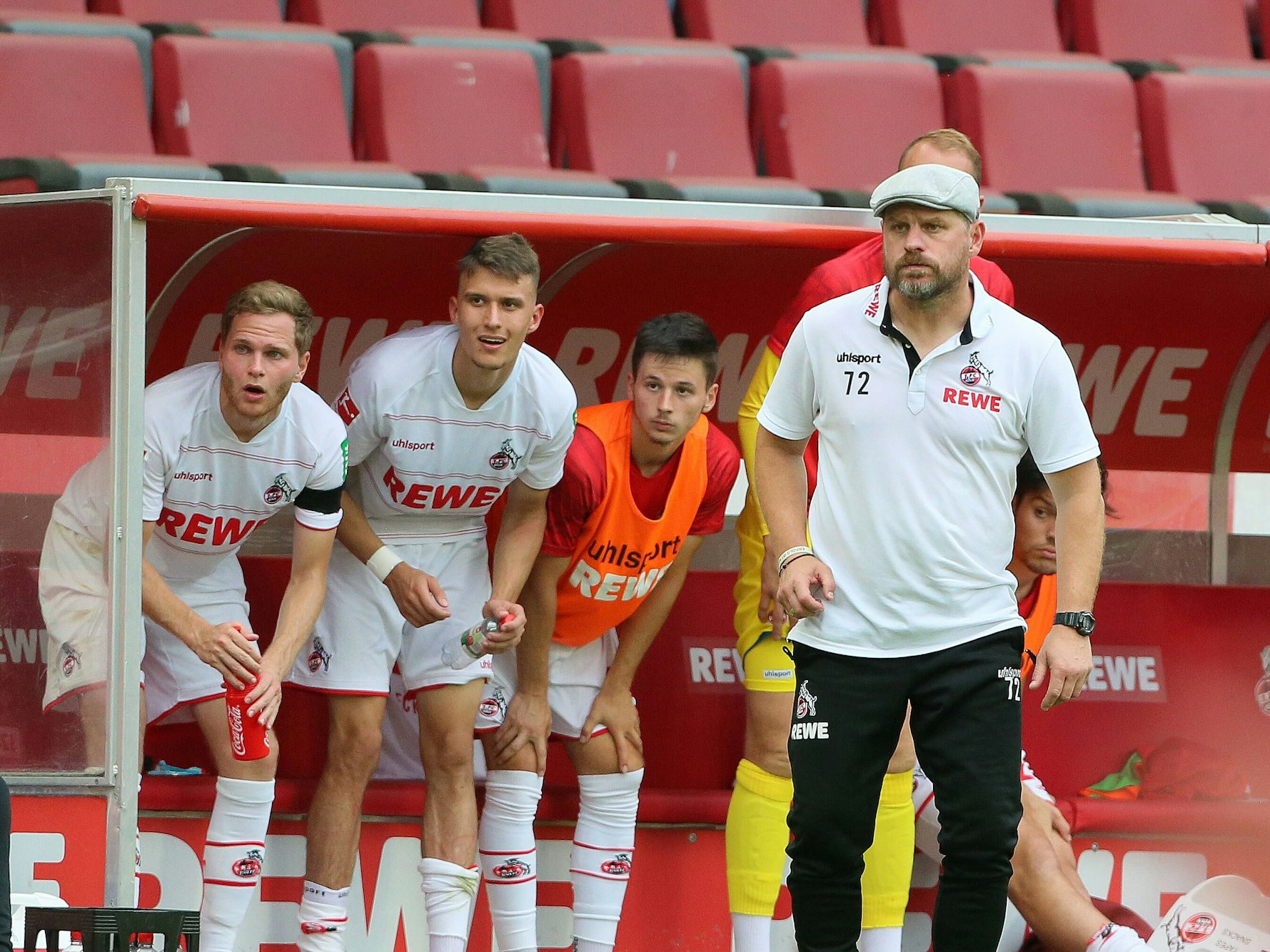Benno Schmitz, Dejan Ljubicic, Tomas Ostrak und Chefcoach Steffen Baumgart mit überraschten Blicken von der Bank beim Bundesliga-Auftaktsieg des FC gegen Hertha BSC.