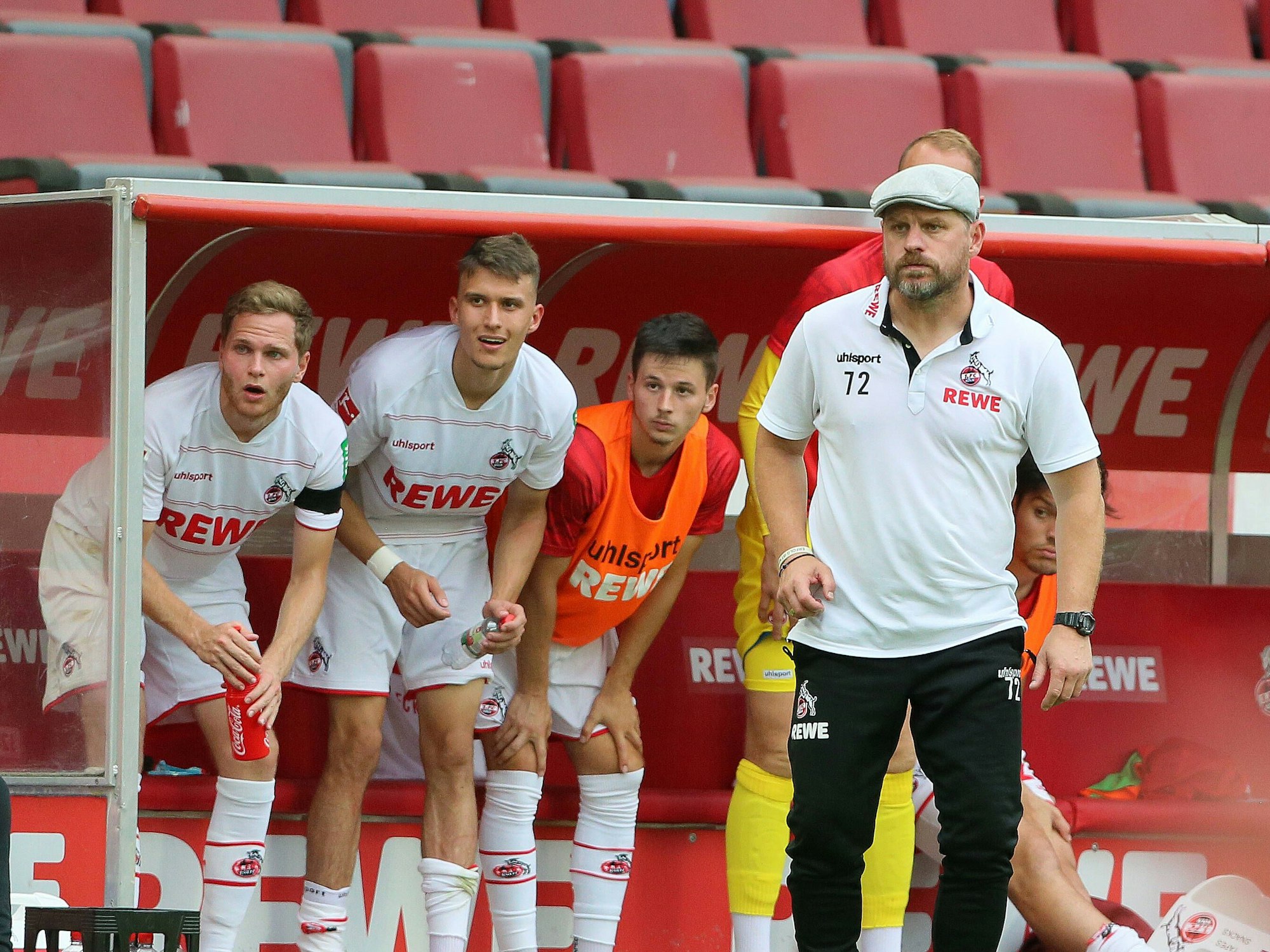 Benno Schmitz, Dejan Ljubicic, Tomas Ostrak und Chefcoach Steffen Baumgart mit überraschten Blicken von der Bank beim Bundesliga-Auftaktsieg des FC gegen Hertha BSC.