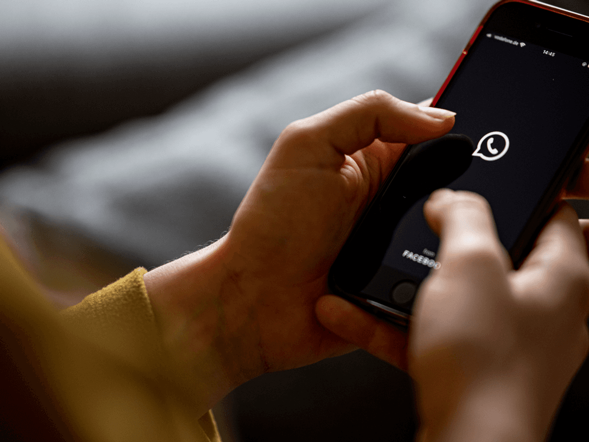 Das Bild zeigt eine Frau mit einem Handy in der Hand auf dem das WhatsApp-Logo abgebildet ist. Es wurde am 24. April 2021 aufgenommen.