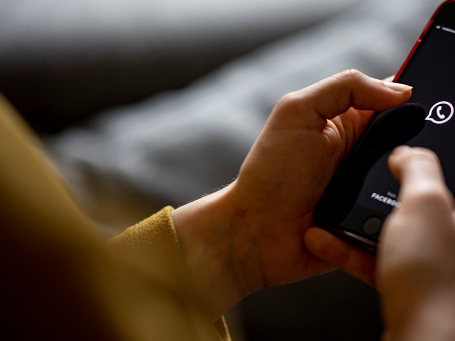 Das Bild zeigt eine Frau mit einem Handy in der Hand auf dem das WhatsApp-Logo abgebildet ist. Es wurde am 24. April 2021 aufgenommen.