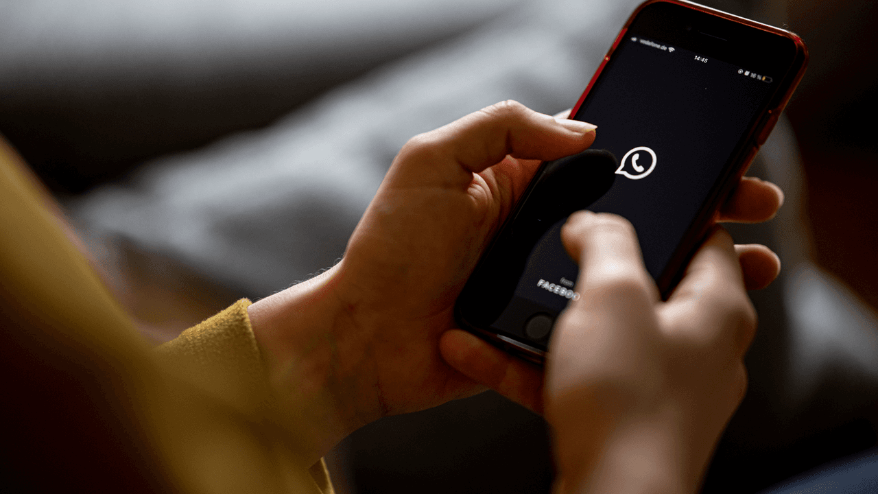 Das Bild zeigt eine Frau mit einem Handy in der Hand auf dem das WhatsApp-Logo abgebildet ist. Es wurde am 24. April 2021 aufgenommen.