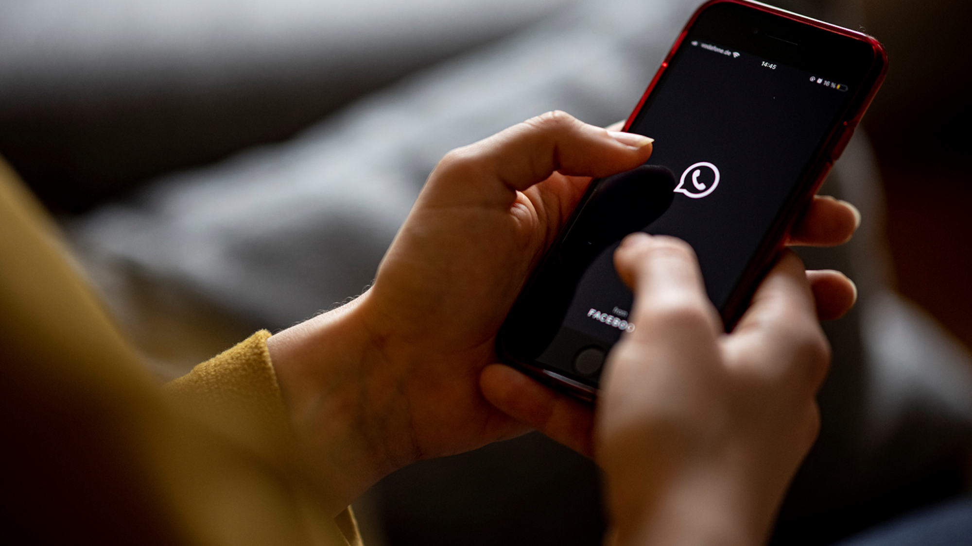 Das Bild zeigt eine Frau mit einem Handy in der Hand auf dem das WhatsApp-Logo abgebildet ist. Es wurde am 24. April 2021 aufgenommen.