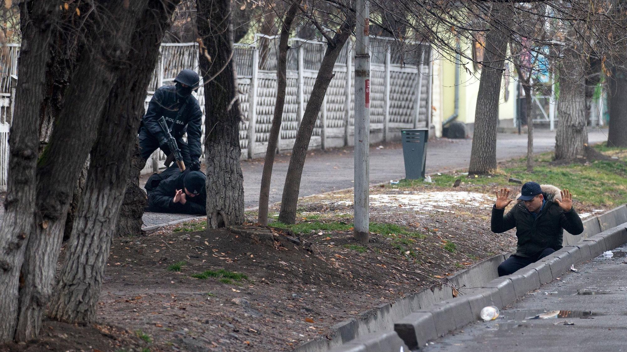 Ein bewaffneter Polizist nimmt am Samstag (8. Januar) zwei Protestanten in Almaty fest. Es seien in Kasachstan mittlerweile fast 6000 Menschen festgenommen worden, darunter viele Ausländer, hieß es. Bei den schweren Unruhen sind offiziellen Angaben zufolge 164 Menschen getötet worden.