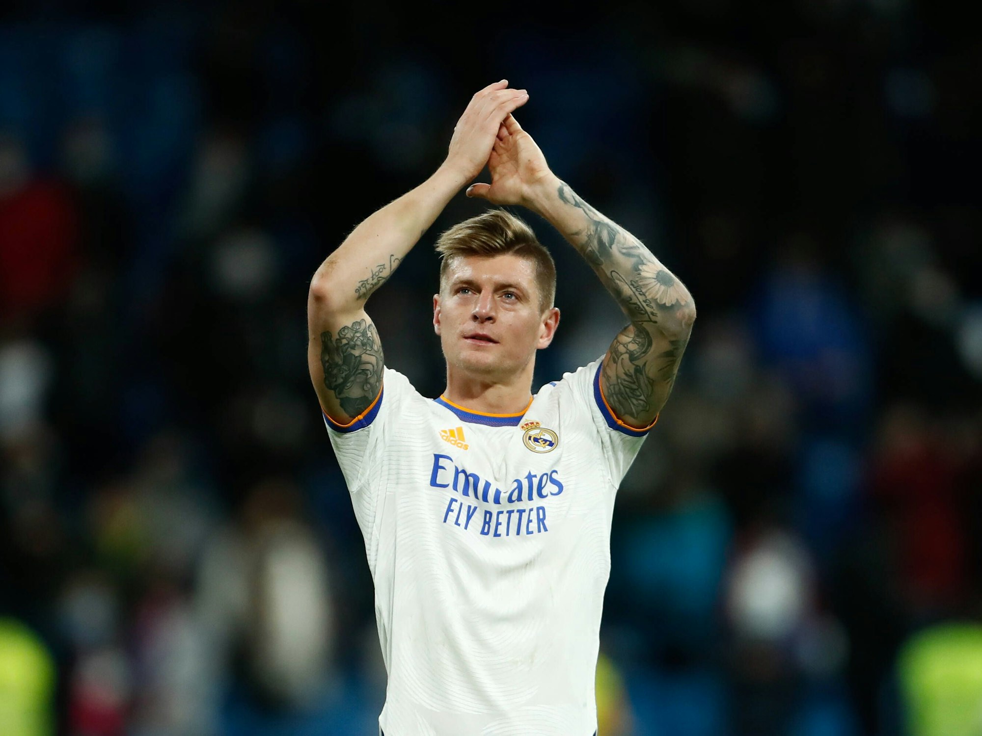 Toni Kroos hat die Hände über dem Kopf und applaudiert den Fans.