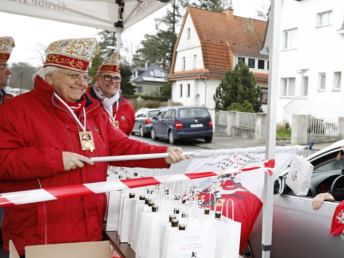Präsident Hans-Jo Fichna von der KG Große Dünnwalder überreicht Orden und einen "Büggel voll Fasteloven“ an ein Vereinsmitglied im Auto.