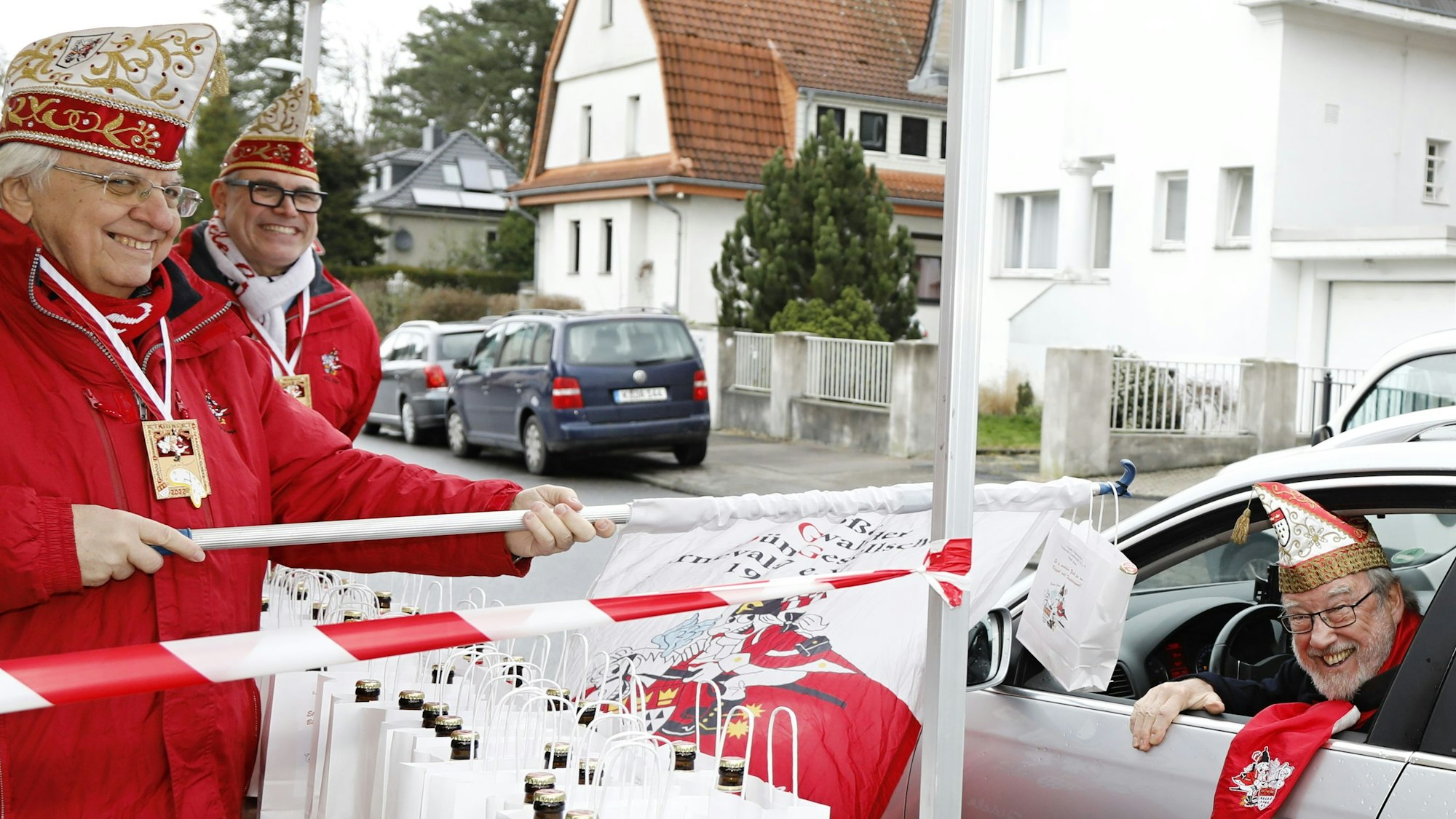 Präsident Hans-Jo Fichna von der KG Große Dünnwalder überreicht Orden und einen "Büggel voll Fasteloven“ an ein Vereinsmitglied im Auto.