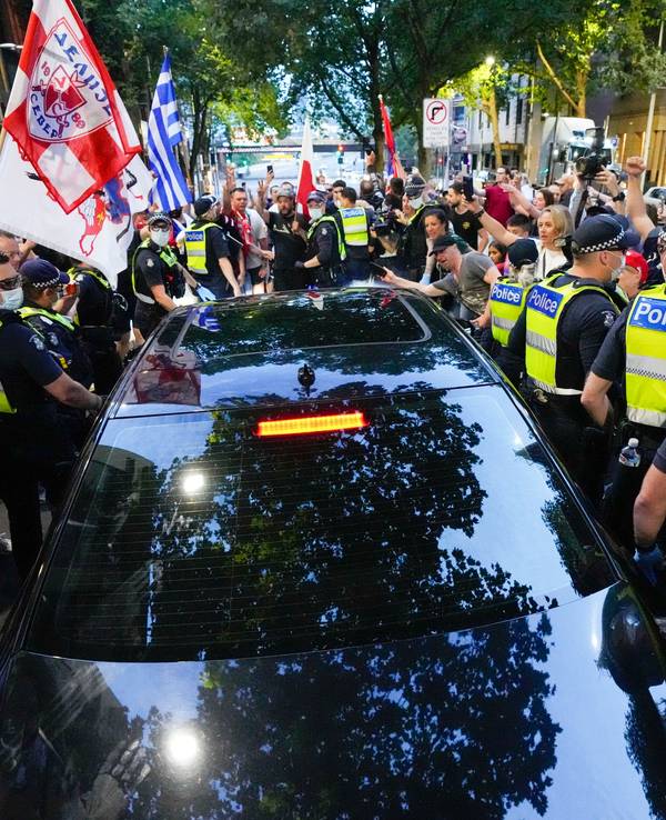 Anhänger des serbischen Tennisspielers Novak Djokovic stehen um ein von der Polizei umringtes Fahrzeug, das das Büro eines Anwalts verlässt.
