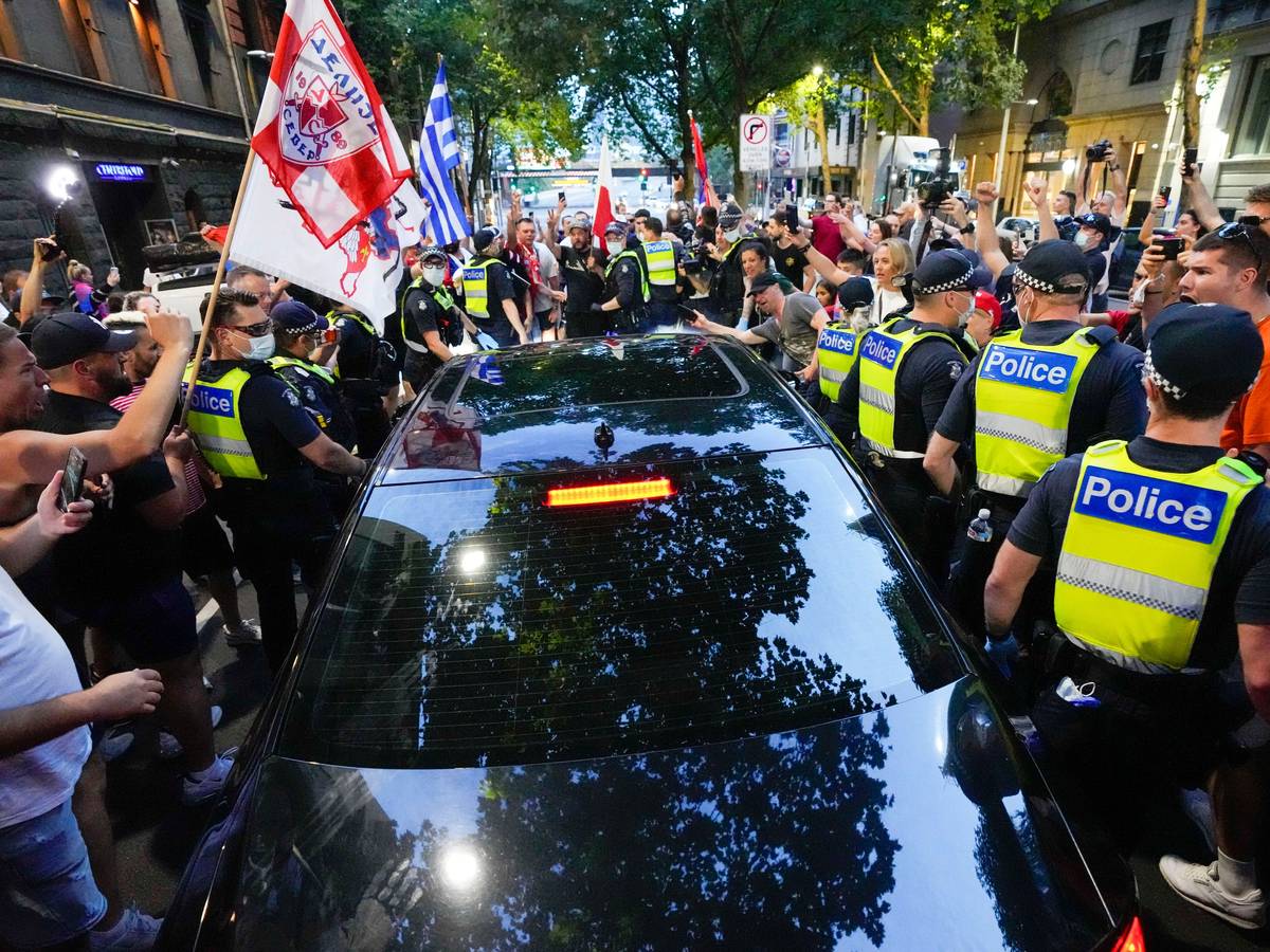 Anhänger des serbischen Tennisspielers Novak Djokovic stehen um ein von der Polizei umringtes Fahrzeug, das das Büro eines Anwalts verlässt.