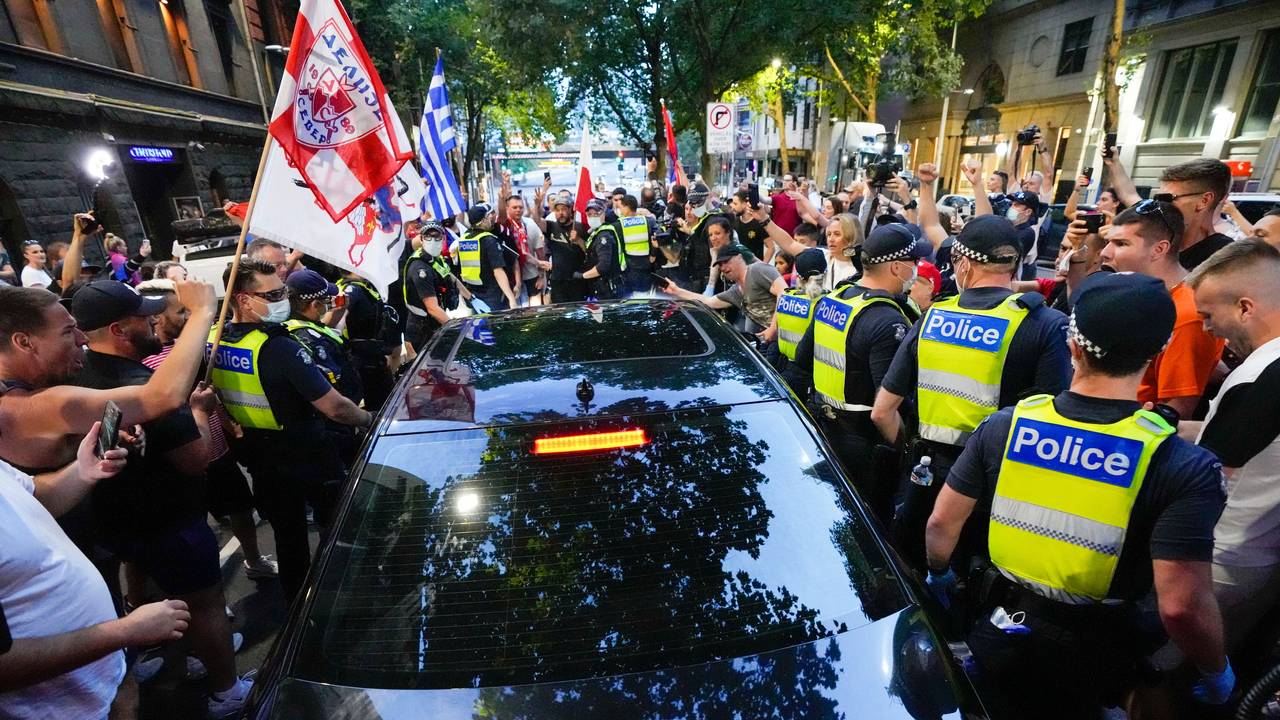 Anhänger des serbischen Tennisspielers Novak Djokovic stehen um ein von der Polizei umringtes Fahrzeug, das das Büro eines Anwalts verlässt.