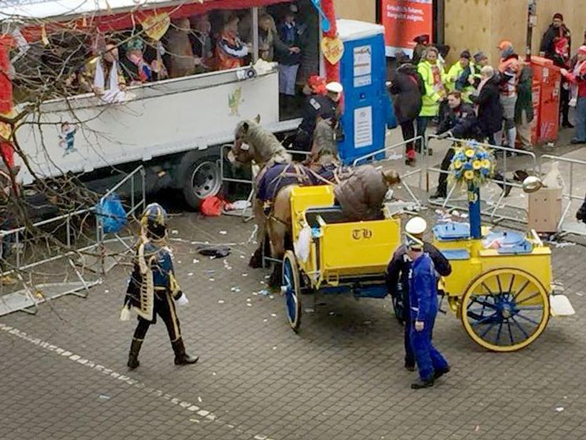 Eine Kutsche mit Pferden steht im Rosenmontagszug vor einem Tribünenwagen.
