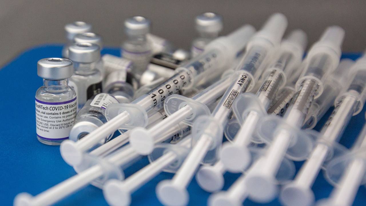 Spritzen und Fläschchen mit dem Impfstoff COVID-19 von Pfizer-BioNTech liegen auf einer Arbeitsfläche.