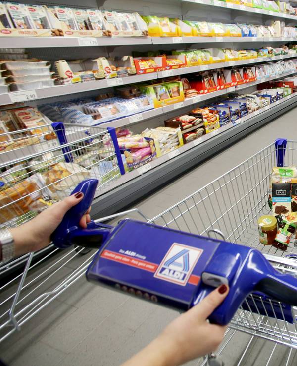 Eine Person schiebt einen befüllten Einkaufswagen durch eine Aldi Nord Filiale.