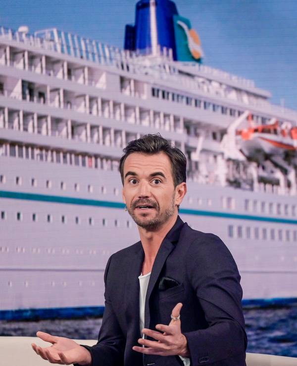 Der Moderator Florian Silbereisen sitzt bei der Aufzeichnung des großen Jahresrückblicks „Menschen 2019“ auf der Bühne. Im Hintergrund ist das ZDF-„Traumschiff“ zu sehen.