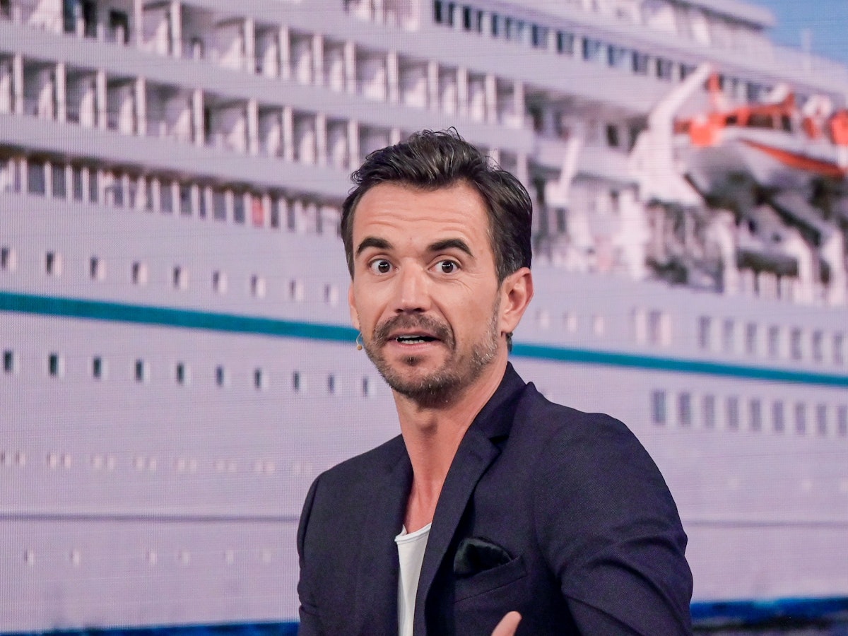 Der Moderator Florian Silbereisen sitzt bei der Aufzeichnung des großen Jahresrückblicks „Menschen 2019“ auf der Bühne. Im Hintergrund ist das ZDF-„Traumschiff“ zu sehen.