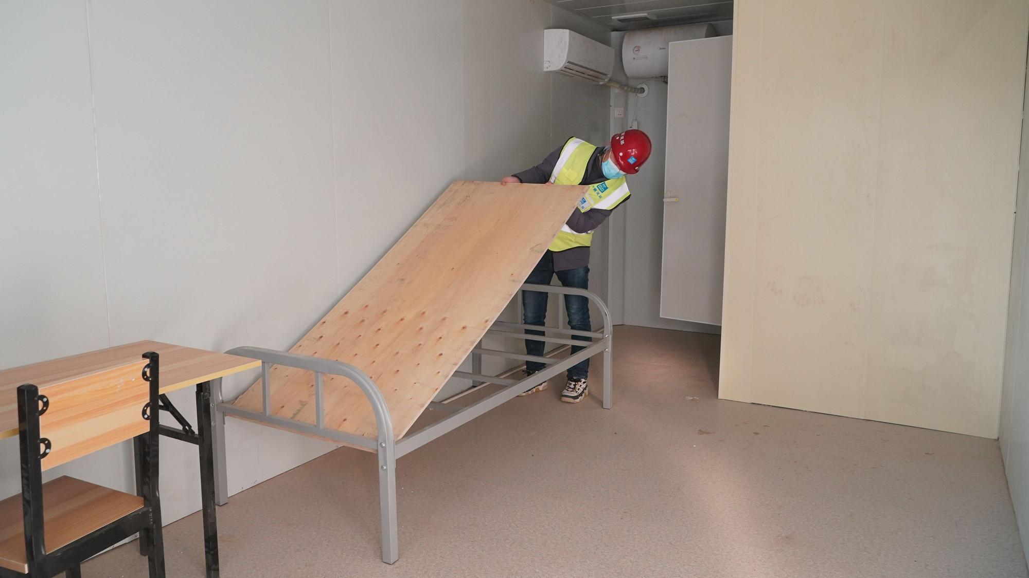 Ein Arbeiter baut auf der Baustelle des Quarantänezentrums Huangzhuang Apartment in einer Unterkunft ein Bett zusammen.