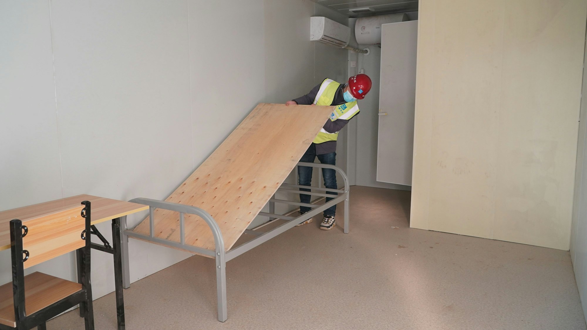 Ein Arbeiter baut auf der Baustelle des Quarantänezentrums Huangzhuang Apartment in einer Unterkunft ein Bett zusammen.