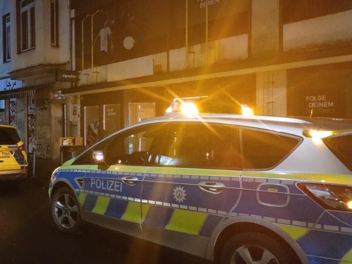 Zwei Streifenwagen stehen vor Häusern in Köln.