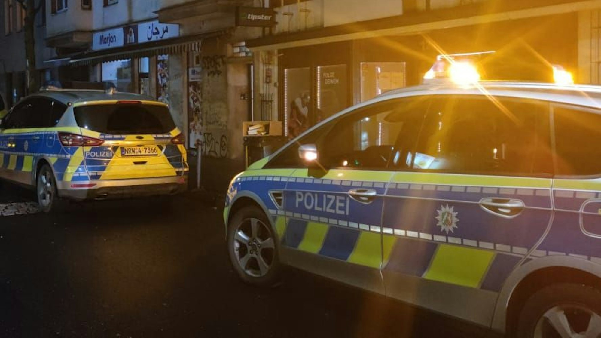 Zwei Streifenwagen stehen vor Häusern in Köln.