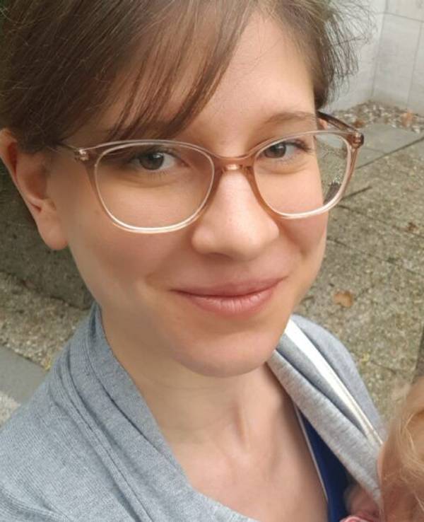 Kölnerin Alexandra Jahnz schaut in die Kamera und trägt eines ihrer Kinder auf dem Arm.