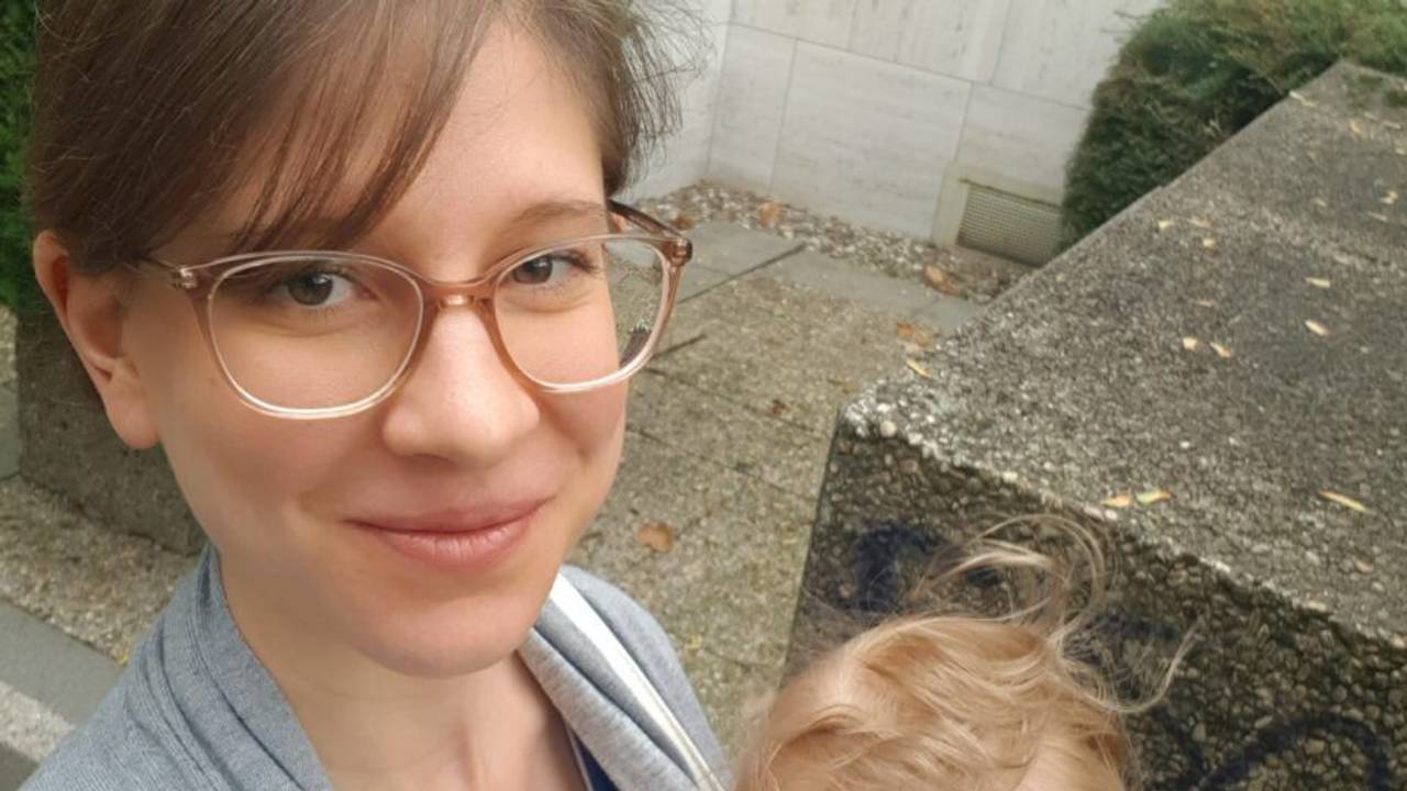 Kölnerin Alexandra Jahnz schaut in die Kamera und trägt eines ihrer Kinder auf dem Arm.