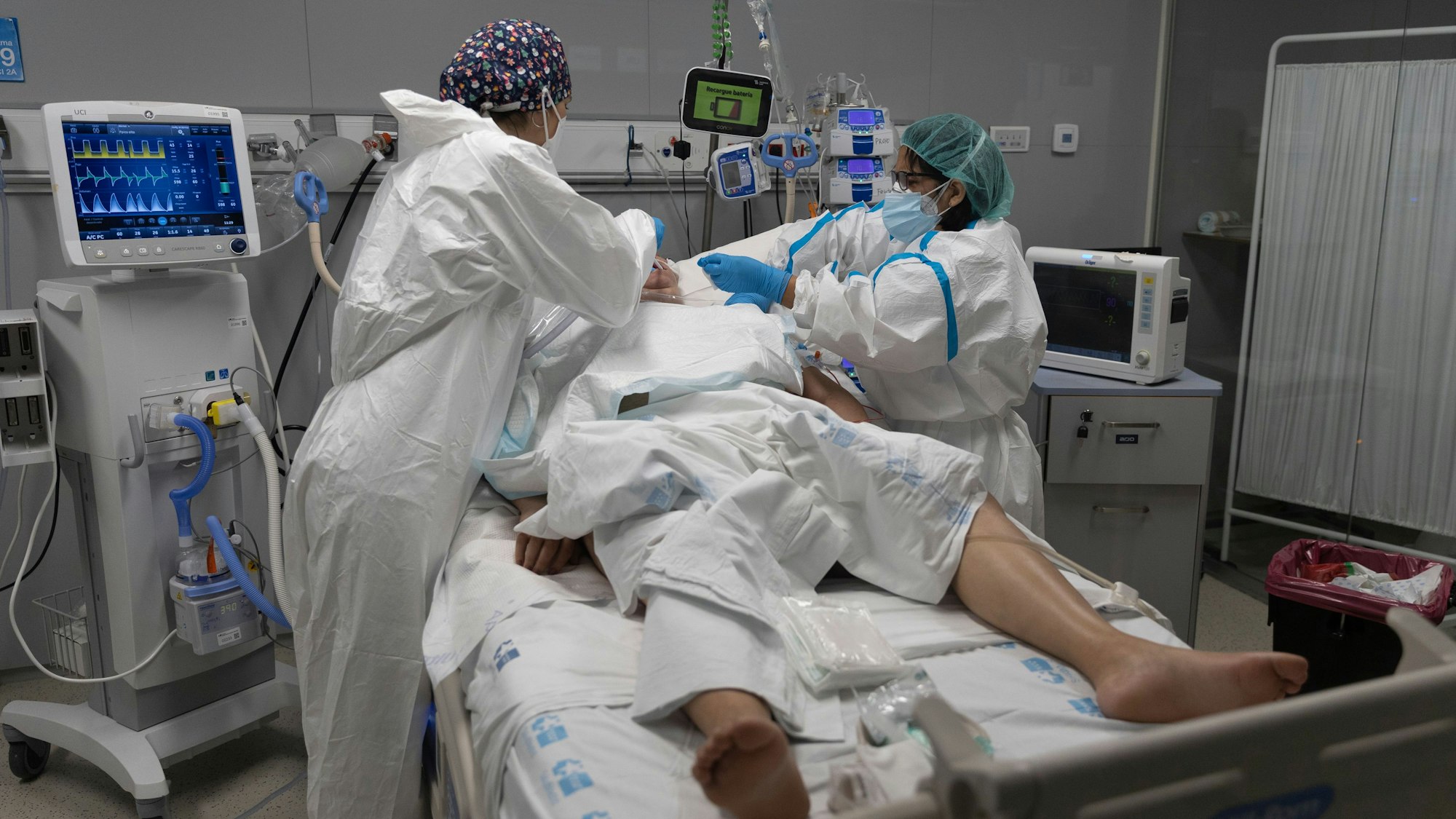 Mitarbeiter des Gesundheitswesens behandeln einen Patienten, der in die Intensivstation des Krankenhauses Isabel Zendal in Madrid eingeliefert wurde.