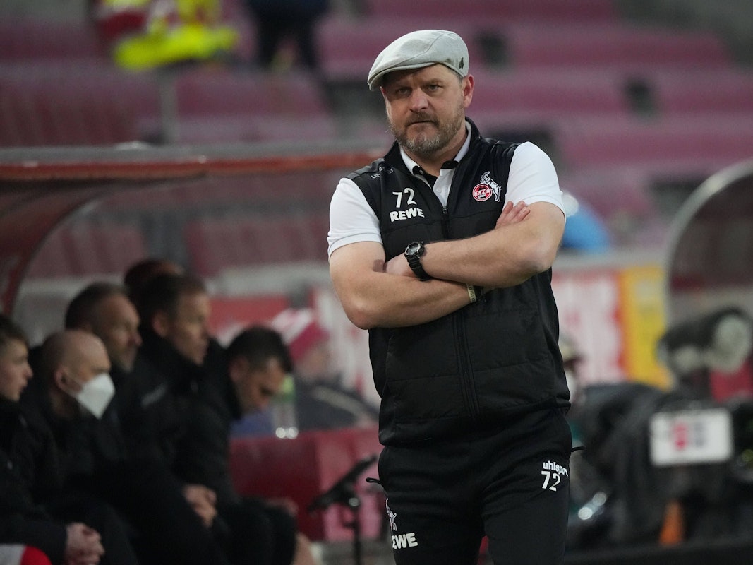 Steffen Baumgart beobachtet mit verschränkten Armen das Spiel seines 1. FC Köln gegen den FC Bayern München.