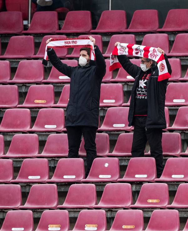 Zwei Fans des 1. FC Köln stehen auf der Tribüne und halten ihre Schals in die Höhe