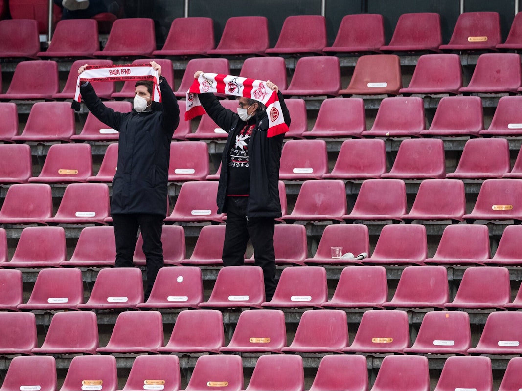 Zwei Fans des 1. FC Köln stehen auf der Tribüne und halten ihre Schals in die Höhe
