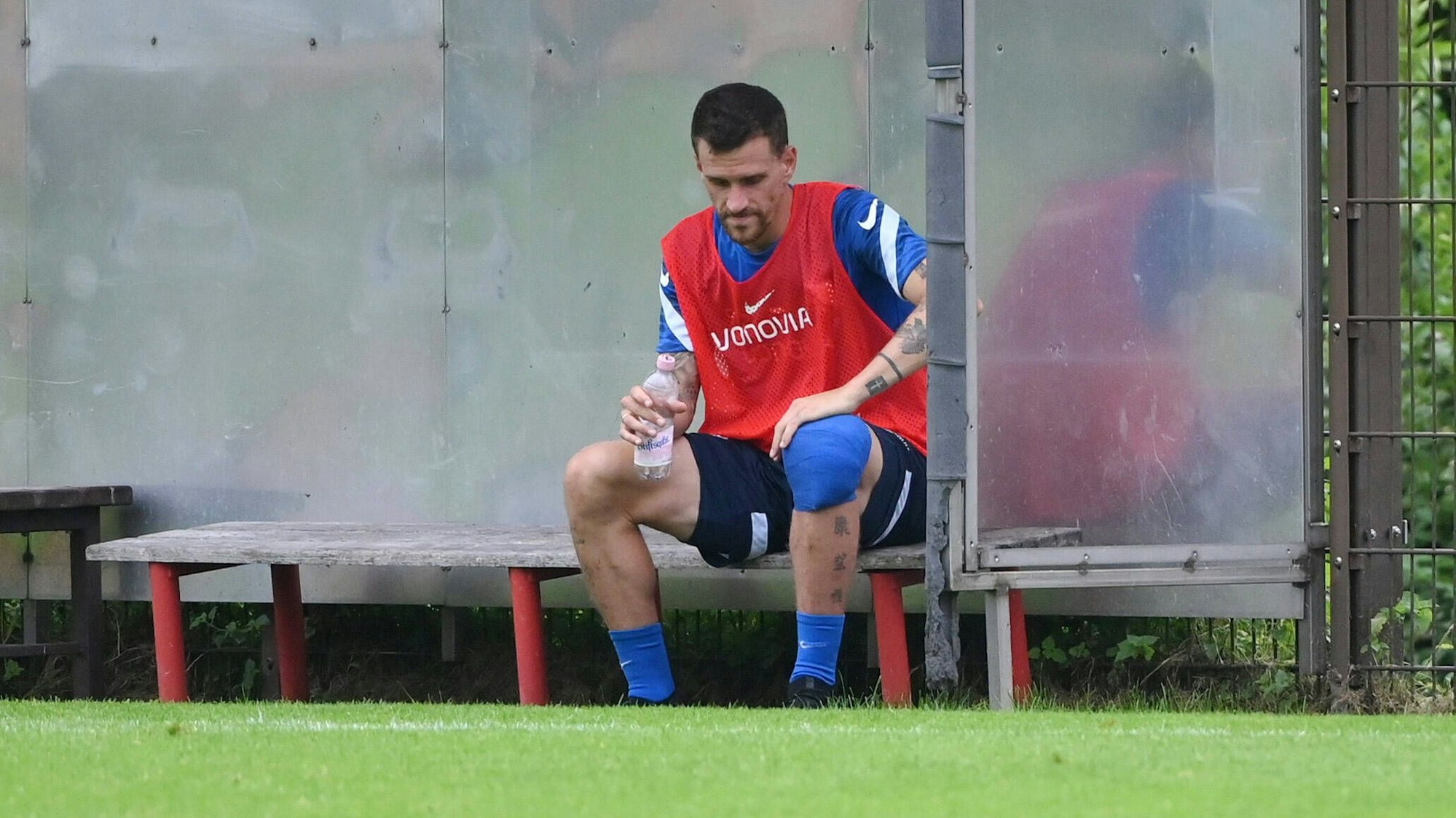 Simon Zoller sitzt mit bandagiertem Knie auf der Bank