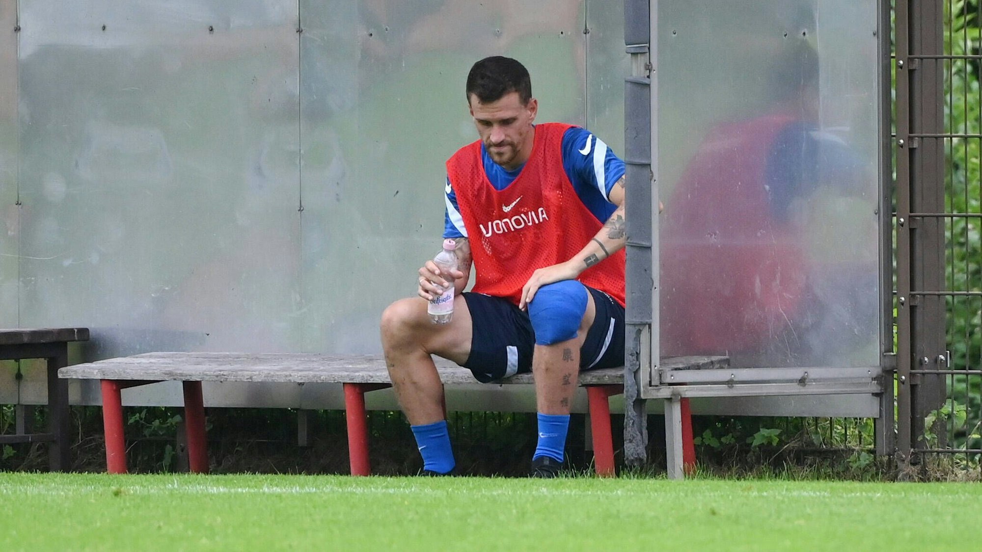 Simon Zoller sitzt mit bandagiertem Knie auf der Bank