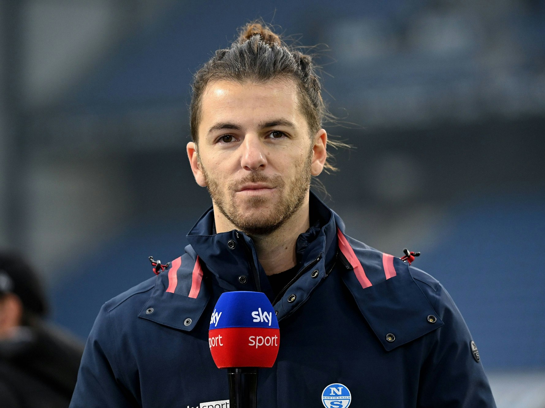 Riccardo Basile steht mit einem Sky-Mikro am Spielfeldrand.