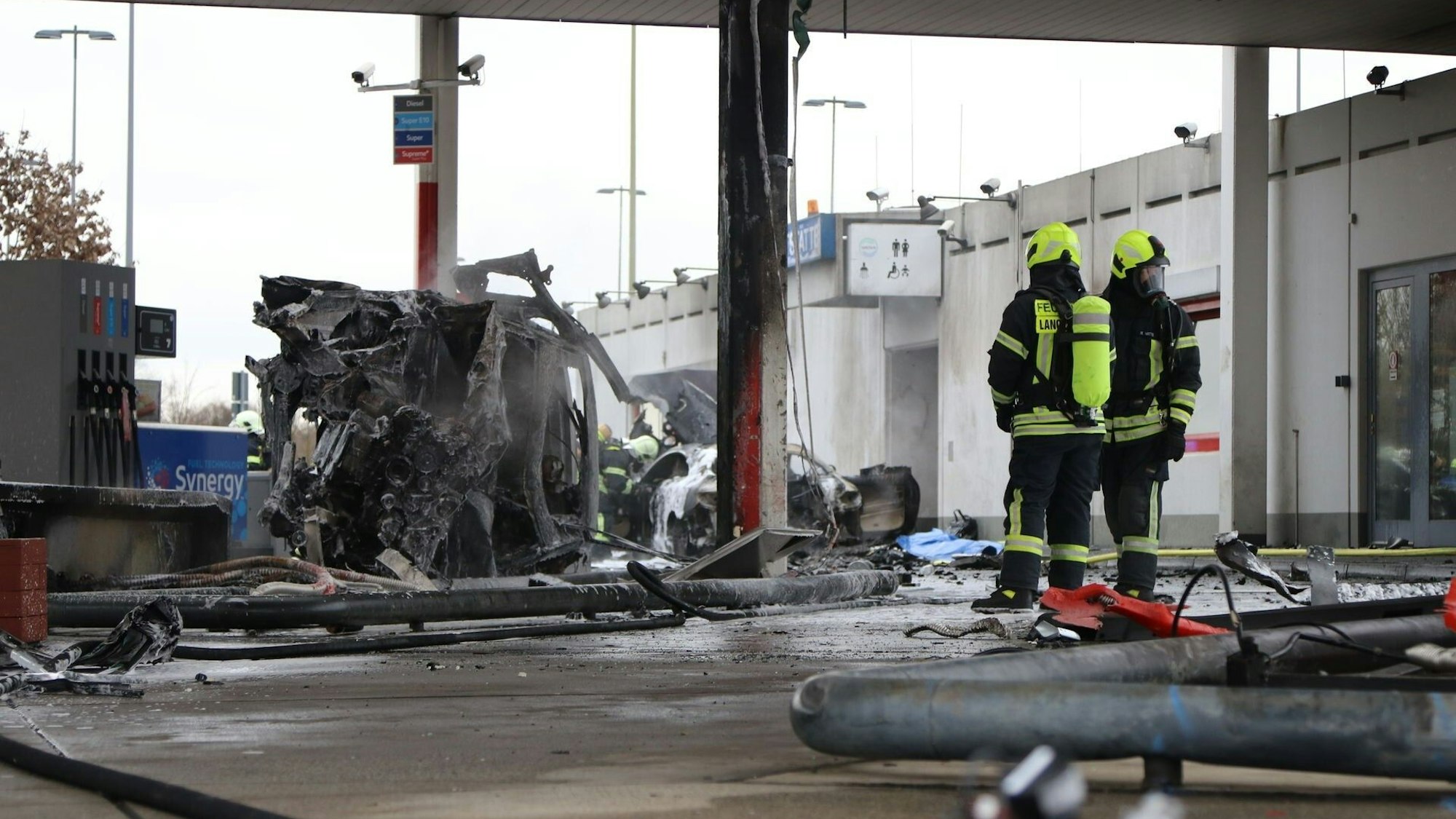 Zwei Feuerwehrleute haben das Feuer an der Tankstelle an der Autobahnraststätte Langen-Bergheim am 17. Januar 2022 gelöscht. Auf dem Bild sieht man einen ausgebrannten PKW.