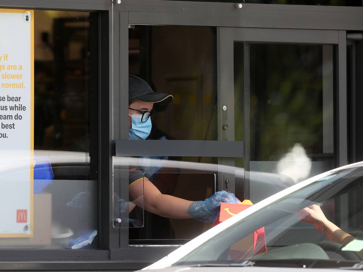 Eine Mitarbeiterin überreicht ein McDonald's-Menü in einem Drive-In (Symbolfoto).