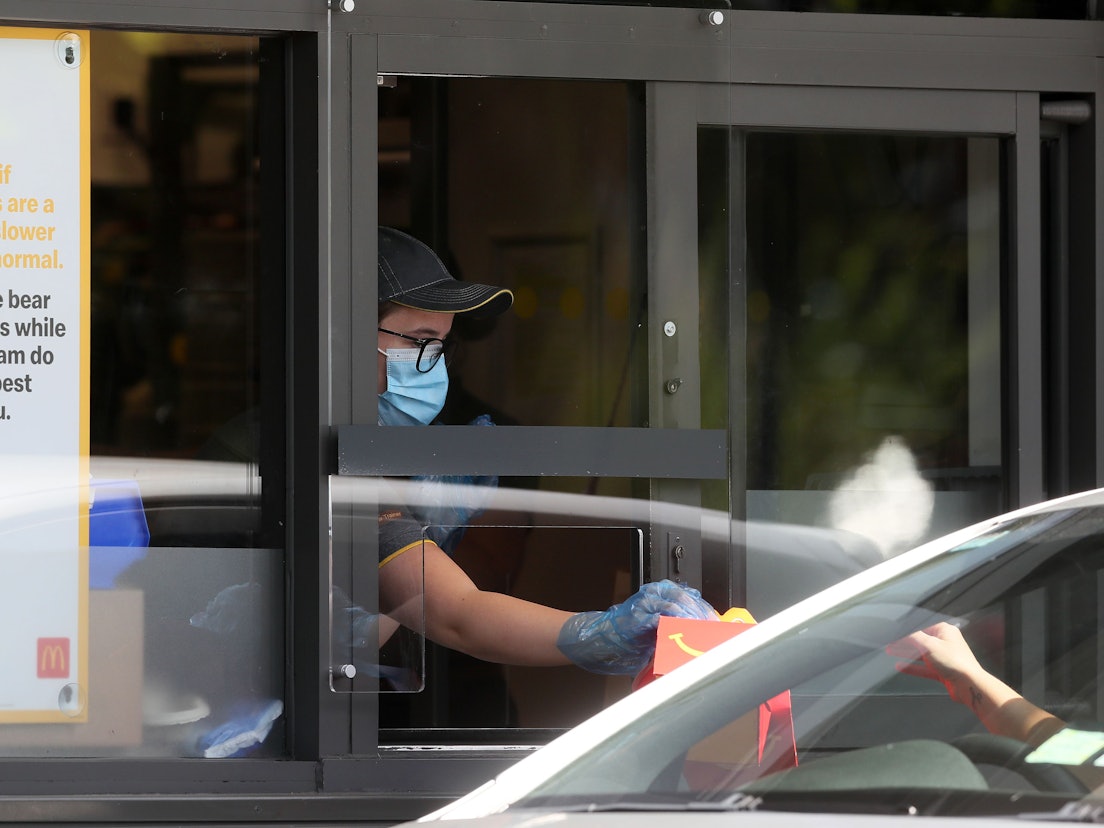 Eine Mitarbeiterin überreicht ein McDonald's-Menü in einem Drive-In (Symbolfoto).