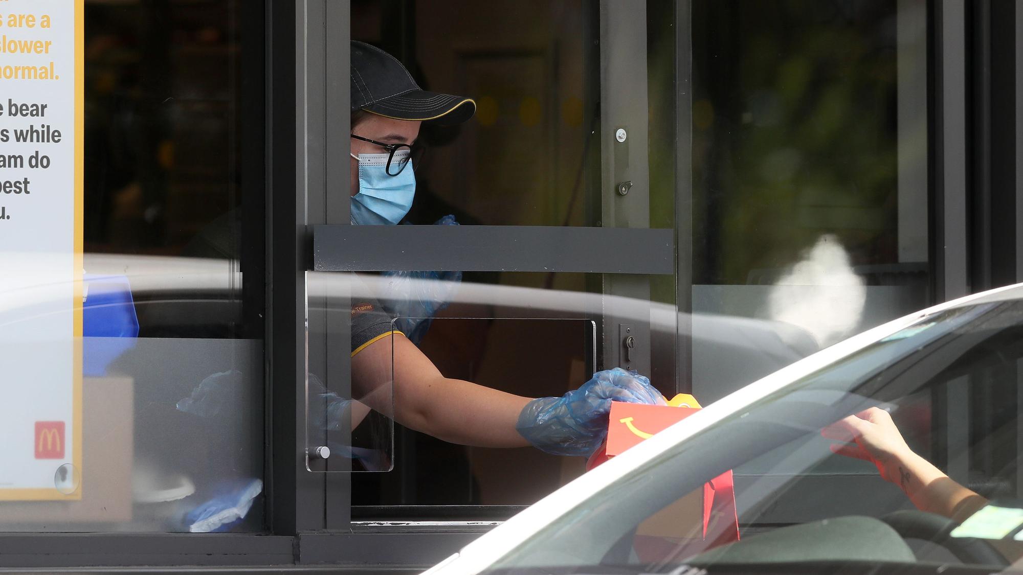 Eine Mitarbeiterin überreicht ein McDonald's-Menü in einem Drive-In (Symbolfoto).