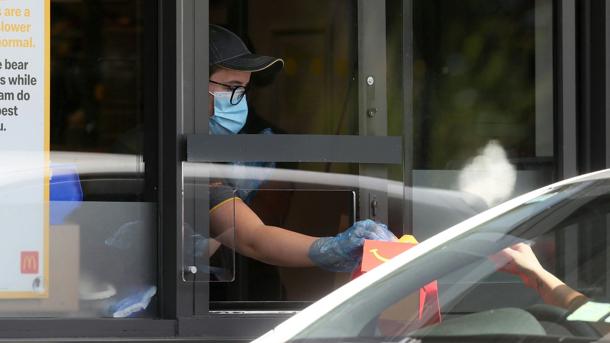 Eine Mitarbeiterin überreicht ein McDonald's-Menü in einem Drive-In (Symbolfoto).