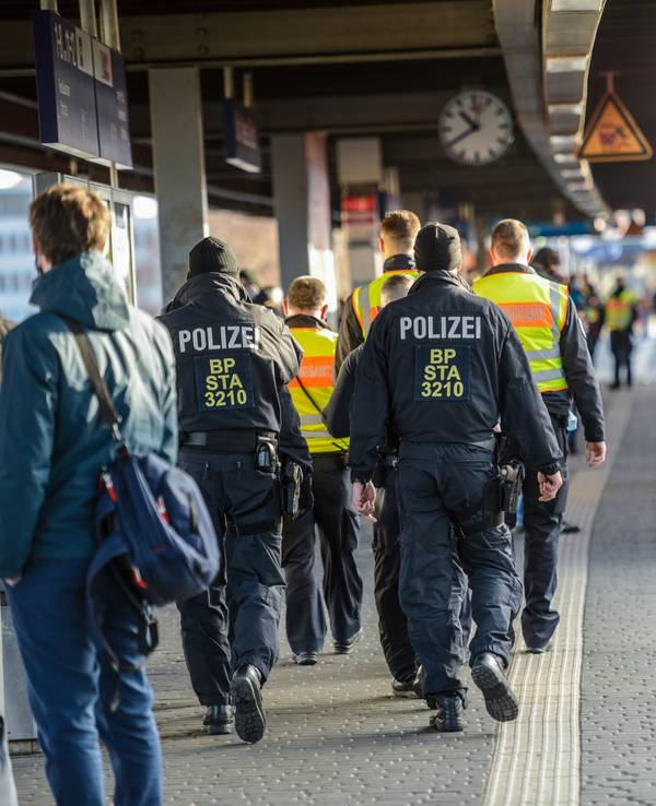 Einsatzkräfte der Bundespolizei laufen am Bahnhof Köln Messe/Deutz auf einem Bahnsteig, an dem eine Bahn hält, entlang.