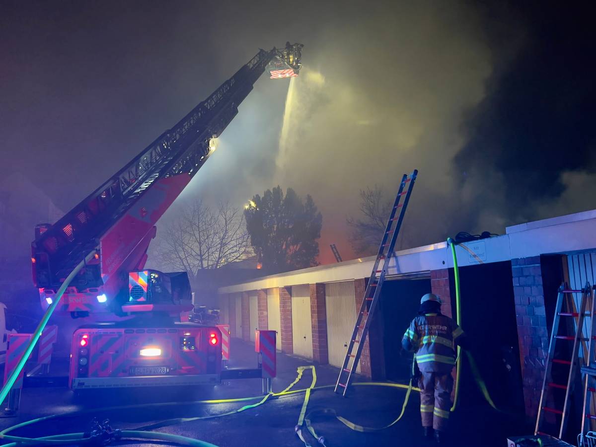 Einsatzkräfte der Feuerwehr vor der brennenden Lagerhalle