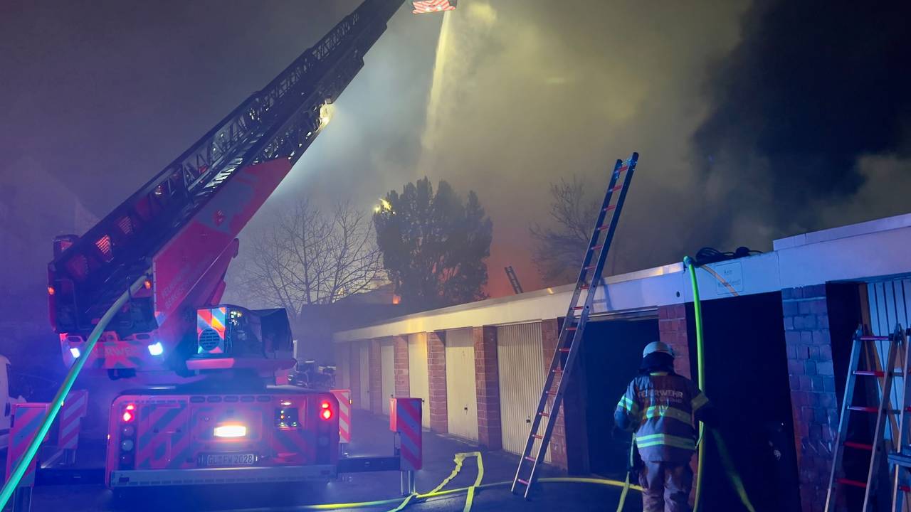 Einsatzkräfte der Feuerwehr vor der brennenden Lagerhalle