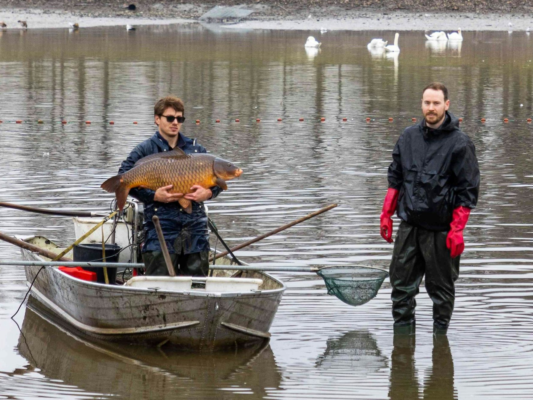 Ein Mann auf einem Boot hält einen Fisch.
