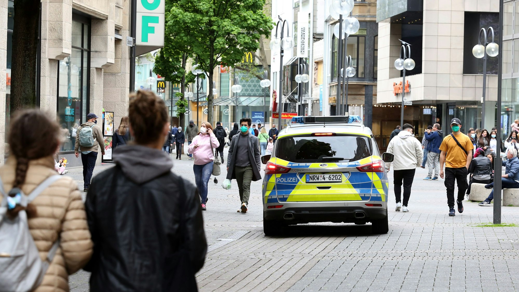 Ein Streifenwagen fährt über die Schildergasse, wo zahlreiche Personen unterwegs sind.