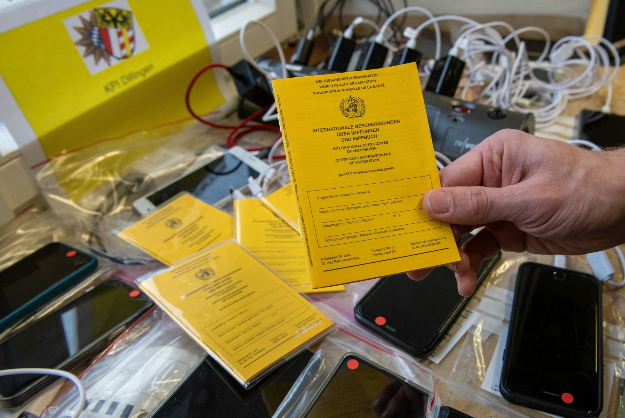 Bei der Kriminalpolizeiinspektion hält ein Ermittler einen Impfpass über Mobiltelefone. Foto vom 17. Januar 2022.