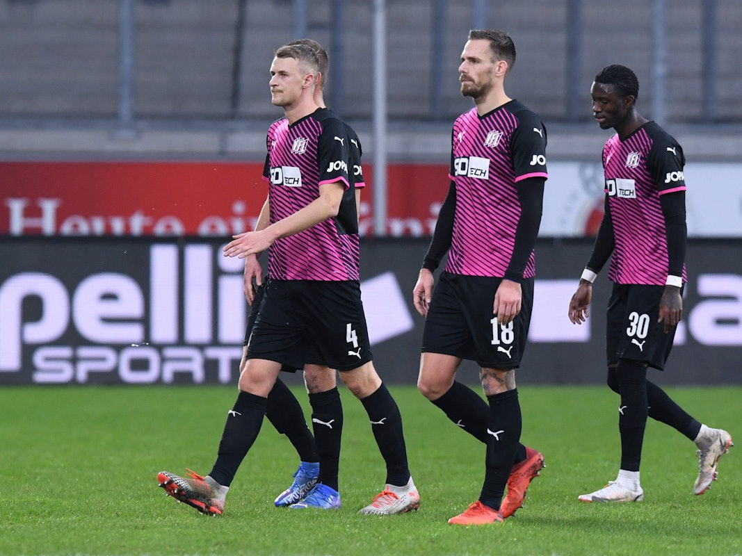 Osnabrücks Aaron Opoku (r) verlässt nach rassistischen Beleidigungen von den Zuschauerrängen mit Teamkollegen das Stadion.
