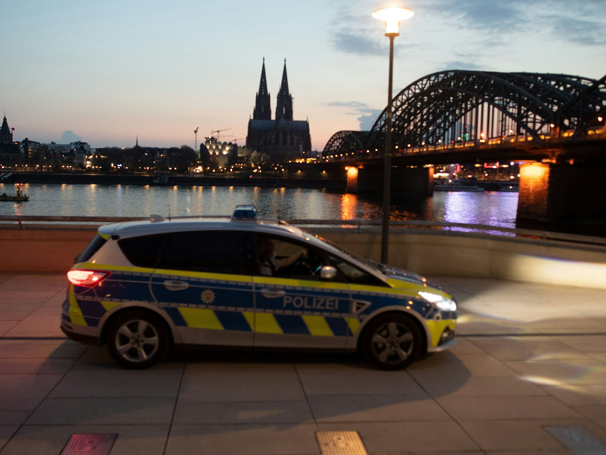Ein Polizeiauto fährt am Rheinufer Streife. Foto von der dpa