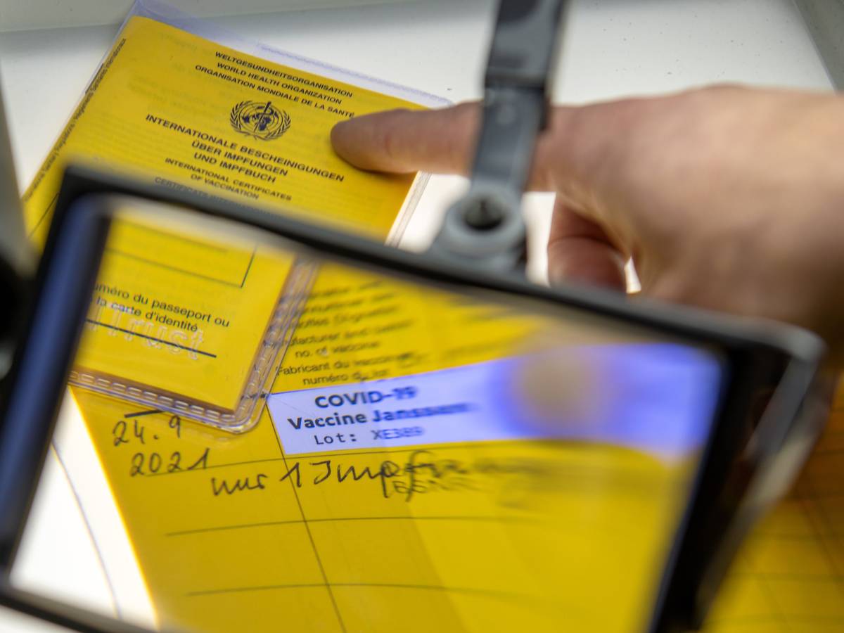 Bei der Kriminalpolizeiinspektion liegen Impfpässe unter einer Lupe, darunter ein aufgeschlagener Impfausweis mit einem Eintrag einer Corona-Impfung Corona-Impfung mit dem Impfstoff Johnson & Johnson.