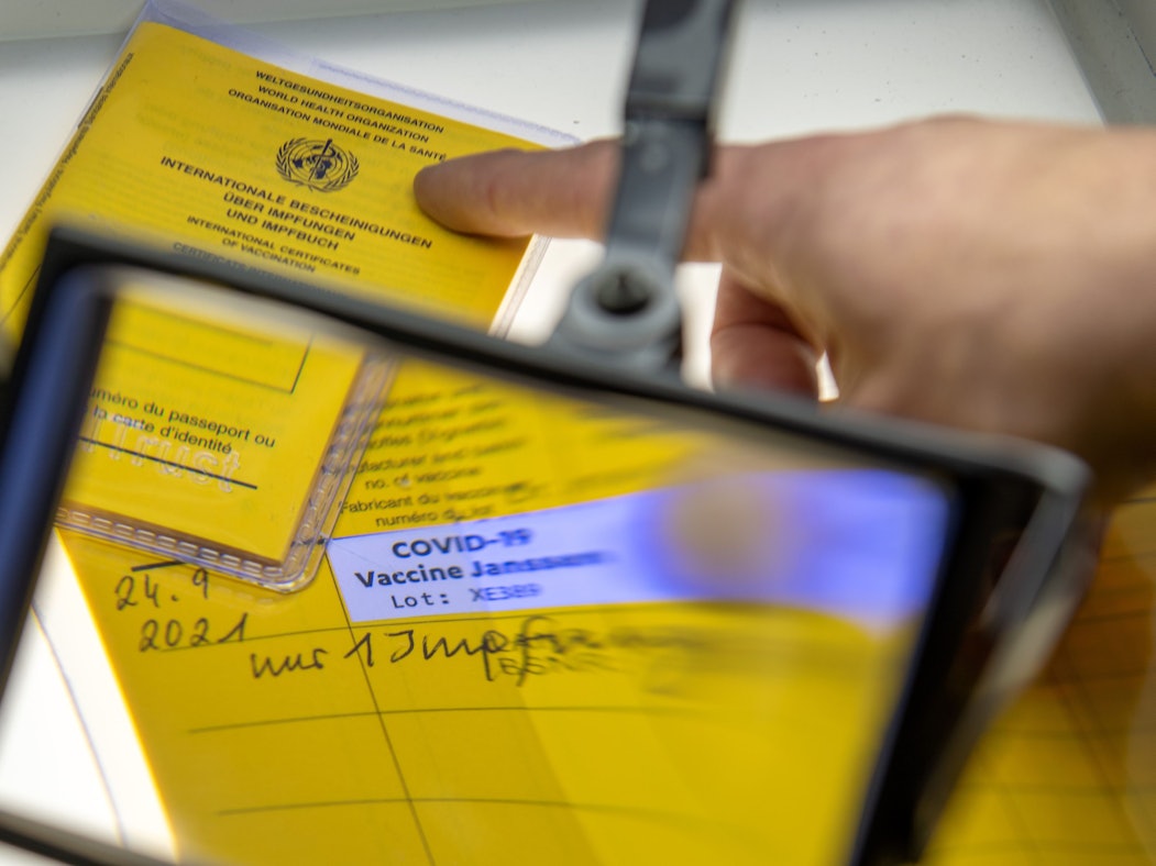 Bei der Kriminalpolizeiinspektion liegen Impfpässe unter einer Lupe, darunter ein aufgeschlagener Impfausweis mit einem Eintrag einer Corona-Impfung Corona-Impfung mit dem Impfstoff Johnson & Johnson.